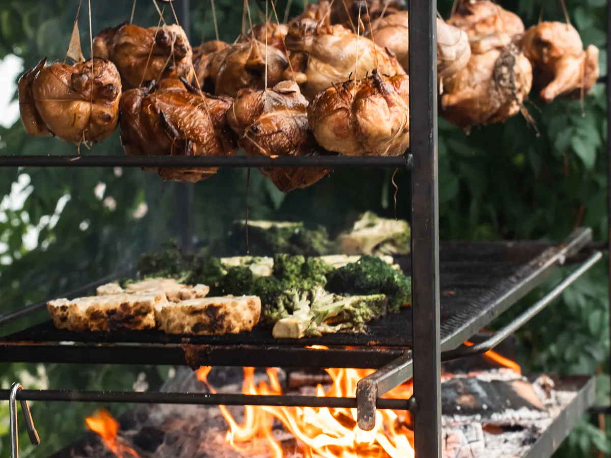 Chickens hanging on top, broccoli on the grill, the fire underneath